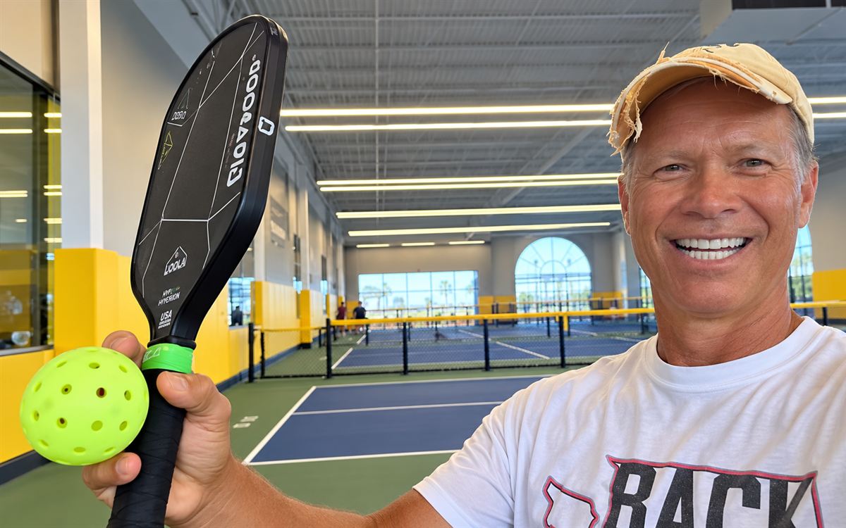 Coach Henry on an indoor pickleball court, paddle and ball in hand